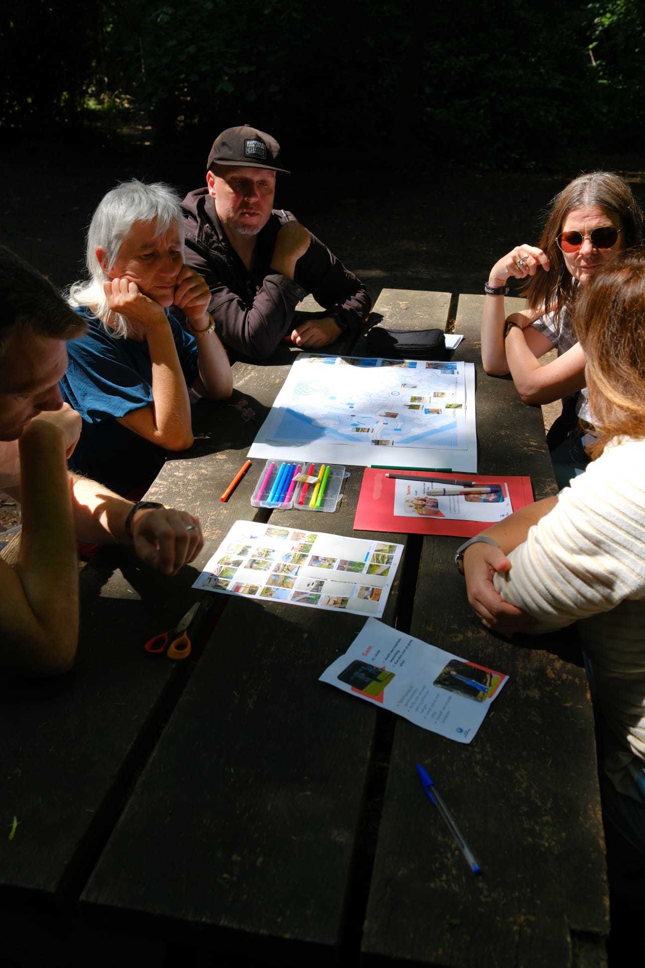 Deelnemers zitten rond een tafel, met daarop papier en kleurpotloden